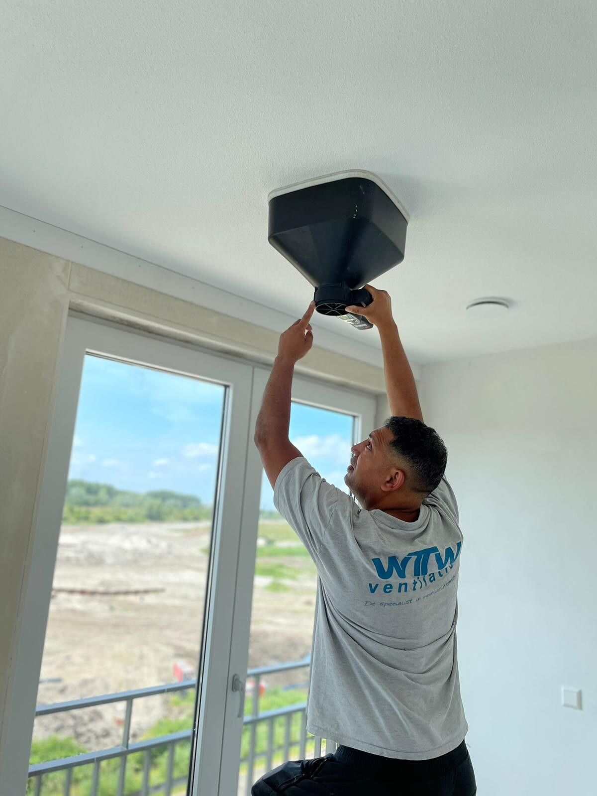 Monteur van WTW Ventilatie plaatst een ventiel in een nieuwbouwwoning